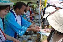 Photo Chairman and Kasumigaura tourism ambassador assisting with the free distribution of tsukudani and other tasty treats.